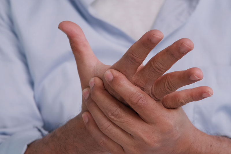 Man feeling his hand because he’s experiencing numbness