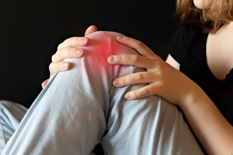 Shot of a woman’s knee, throbbing red with joint pain