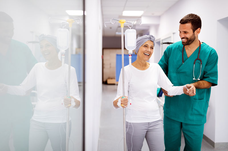 Woman walking with a doctor with an IV drip, smiling