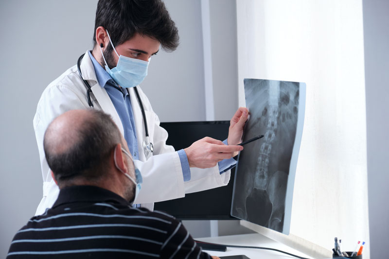young doctor examining x ray of a senior patient